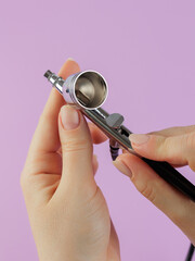 A woman's hand holds an airbrush. Professional tools for manicure. Beauty concept. Place for text.