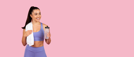 Smiling woman with water bottle and towel post-workout