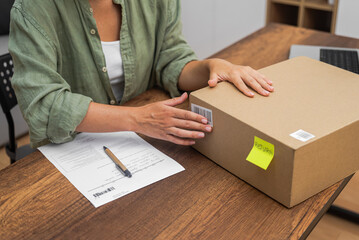 In pursuit of an online shopping refund, a woman places a barcode sticker on a cardboard parcel for...