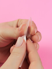 Step-by-step instructions for nail extension on gel tips. Manicure, hands in the foreground. Pink background. Copy space