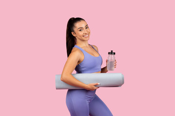 Smiling woman ready for yoga with mat and water