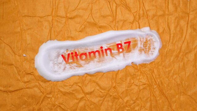 Finger rubs white cream foam wiith animation Vitamin B7 on a yellow background, cosmetology and beauty concept, skin protection