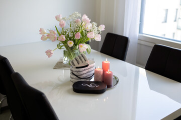 Bouquet of pink tulips and pink candles on a white table. Photo
