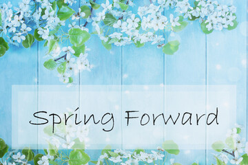 Spring forward sign over a beautiful spring tree blossoms against a peaceful blue rustic wooden background. Image shot from above in flat lay table top view. 