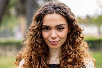 Fototapeta premium portrait of beautiful curly haired woman looking at camera