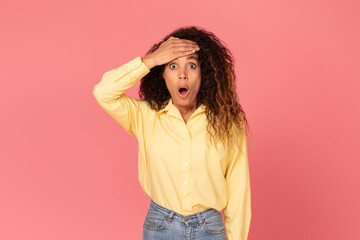 Shocked black woman with hand on forehead, wide-eyed, on pink background