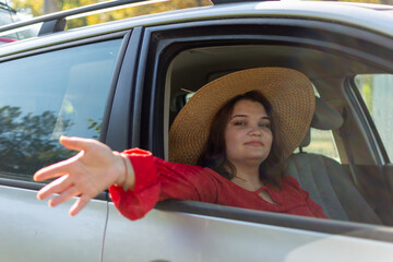Naklejka premium Girl in hat sitting in car with her hand out the window