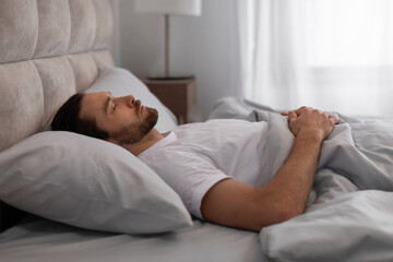 Man sleeping peacefully in bedroom interior