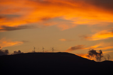 Clean energy power concept with wind turbine on top of a mountain during dramatic sunset in zakynthos, Greece