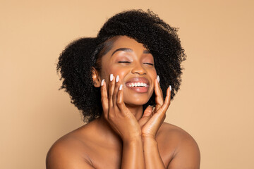 Joyful black woman with curly hair touching her face