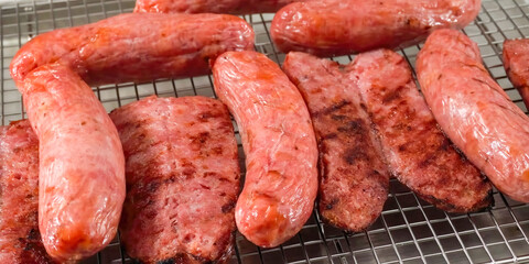 Hot Dog preparation, freshly grilled sausages, close up. Homemade hot dog sausage cooking. Grocery product advertising, menu or package, selective focus.