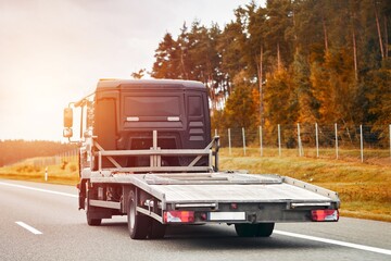 Roadside assistance transports a car with a breakdown on the road. Rollback tow truck. A tow truck...