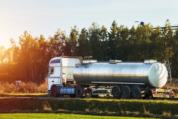 Fototapeta na wymiar Fuel Delivery. Liquid Fuel and Oil Cargo Semi Truck on the Highway. Hauling Petroleum Products. Compressed Gas Carrier Truck in the Evening Light