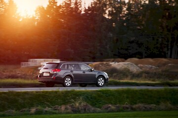 Driving a modern car in the golden hour of dusk. A scenic landscape of forest and road awaits the...