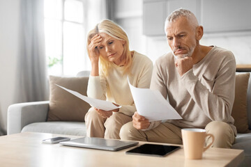 Senior Couple Checking Financial Documents, Sitting On Couch At Home