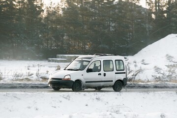 Modern car during snow storm go on the highway. Side view of the car in winter on the road. Necessity of winter tires during slippery and cold weather conditions. Below zero.