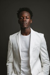 A professional portrait of a black young man wearing a white suit jacket over a T-shirt
