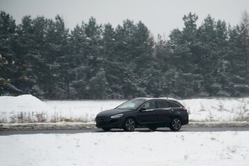 Car on a winter road. Dangerous driving conditions on the highway. Winter tires and undercarriage rust and corrosion concept. Slippery highway.