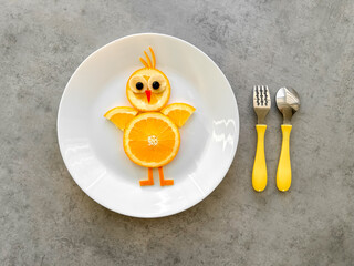 Fun food for kids, orange chicken on gray background, healthy food, serving fruit to a child