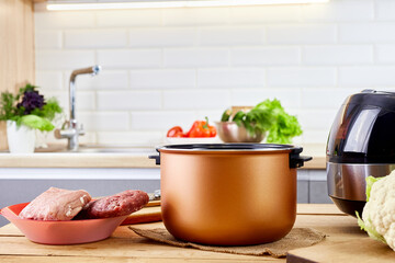 Modern pot of multicooker and products on kitchen table. Capacity for multi cooker at home.