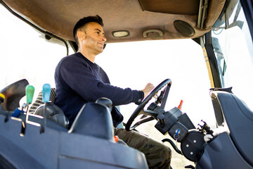 Photo of an adult man driving a tractor in work clothes. Photo of the interior of a field vehicle...