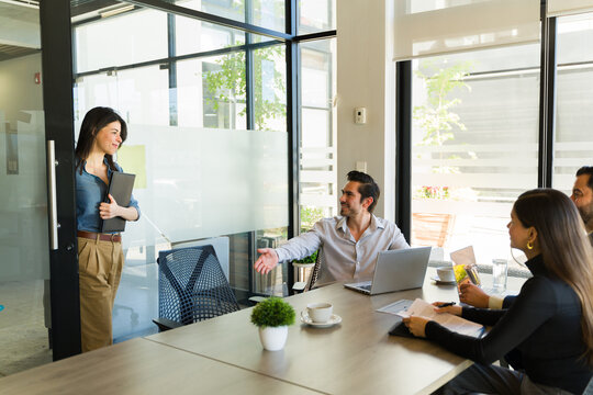 Businessman inviting a woman that just arrived to the meeting to sit down