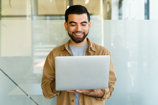Happy tech support guy using a laptop computer while standing in an office