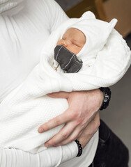 Man holds newborn baby in his arms close-up