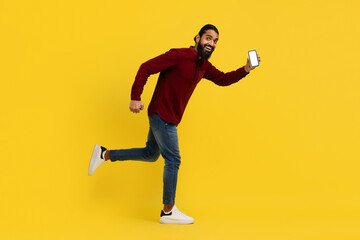 Bearded indian man running with smartphone in his hand