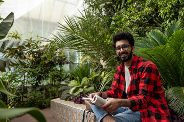 Smiling hindu man in a garden reading a book