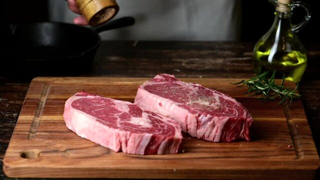 chef seasoning steak with salt and pepper