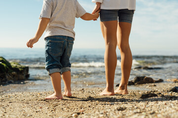 mother and son holding hands on the seashore. psychology of communication with children. family sea...
