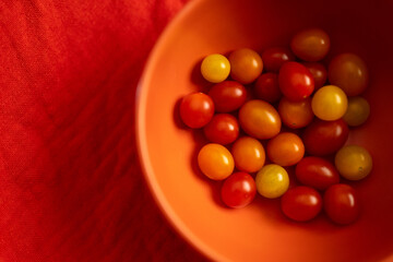 Modern orange bowl with red cherry tomatoes from above