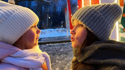 Mom soothes a sad little daughter, they talk face to face, it's winter outside and steam is coming