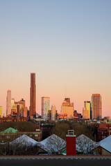 Fototapeta premium New York City Sunrise Skyline with skyscrapers and pink sky, a warm pastel-toned colors of Manhattan Cityscape view from Brooklyn at twilight