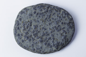 Round, flat, grey sea or river stone textured by erosion.