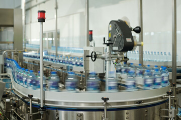 Blurry motion of production line with group of capped plastic bottles with filtered still or...