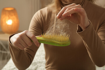 Woman holding detangler hair brush full of hair that has fallen out, loss hair problem 