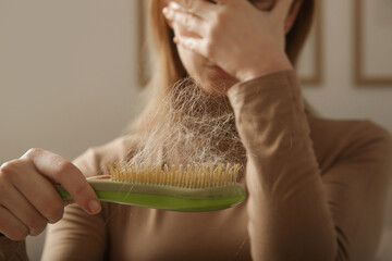 Woman holding detangler hair brush full of hair that has fallen out, loss hair problem 