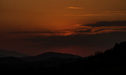 Fototapeta premium Beautiful sunset in the mountains. Sunset View from the Top of a Mountain. Sunset in strong orange tones in Serbia. The sun falls for horizon, a sunset. Shadows are condensed, beautiful clouds.