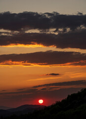 Beautiful sunset in the mountains. Sunset View from the Top of a Mountain. Sunset in strong orange tones in Serbia. The sun falls for horizon, a sunset. Shadows are condensed, beautiful clouds.