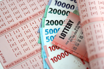 Red lottery ticket lies on pink gambling sheets with indonesian rupiah money bills. Lottery playing...