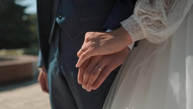handsome groom businessman in a jacket touches his hands close-up to the bride in a white dress during a wedding walk, wedding day, details