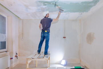 Worker make repairs in new apartment. Man plaster walls and ceilings. High quality photo