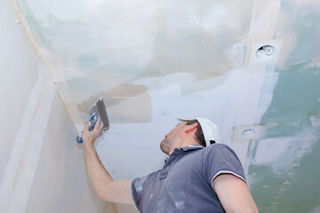 Worker make repairs in new apartment. Man plaster walls and ceilings. High quality photo