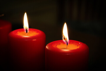 Closeup of two burning candles on a dark background
