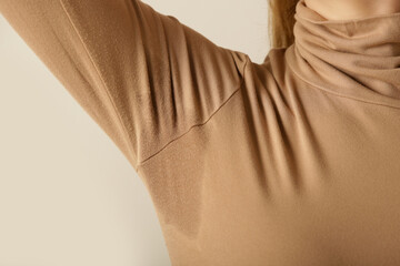  Close up image of woman in beige cotton turtleneck with sweat patch under armpit - obrazy, fototapety, plakaty