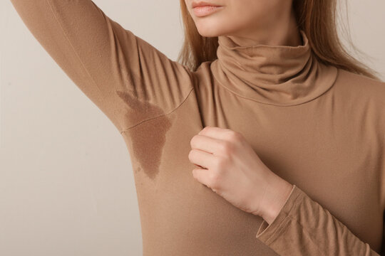  Close up image of woman in beige cotton turtleneck with sweat patch under armpit