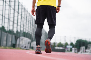 close up Dynamic backside view of a man in comfortable activewear run and jog on the track stadium,...