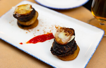 Appetizing timbale with fried morcilla, potatoes, caramelized pear slices and cheese served in...